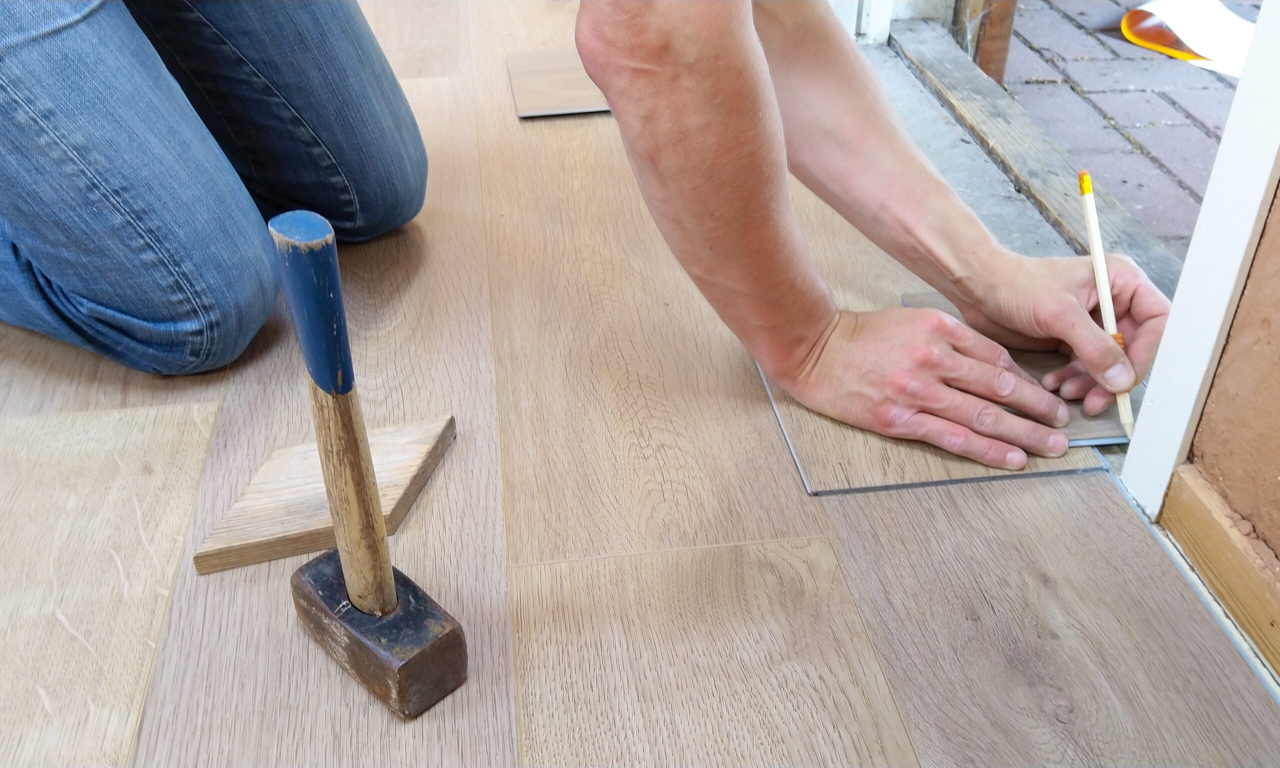 A person's hands working on a wooden floor.