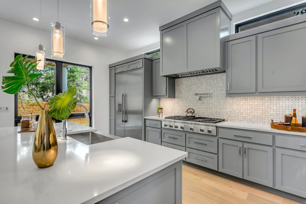 A modern kitchen with gray cabinets and stainless steel appliances.