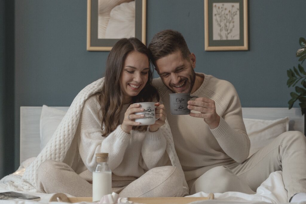 A man and a woman are sitting on a bed enjoying a cup of coffee in the midst of their home renovation.