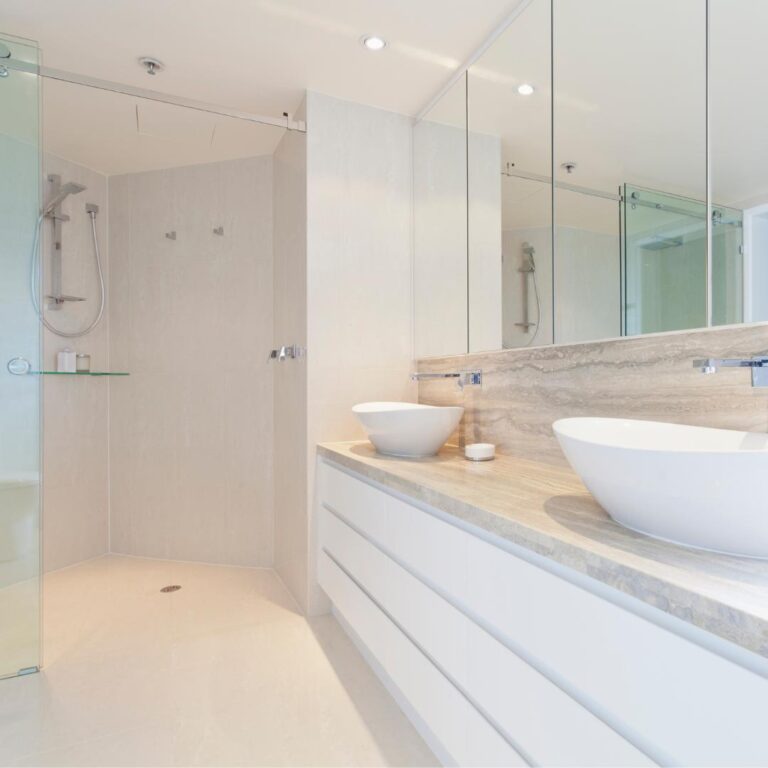 Renovated bathroom with two sinks and a glass shower.